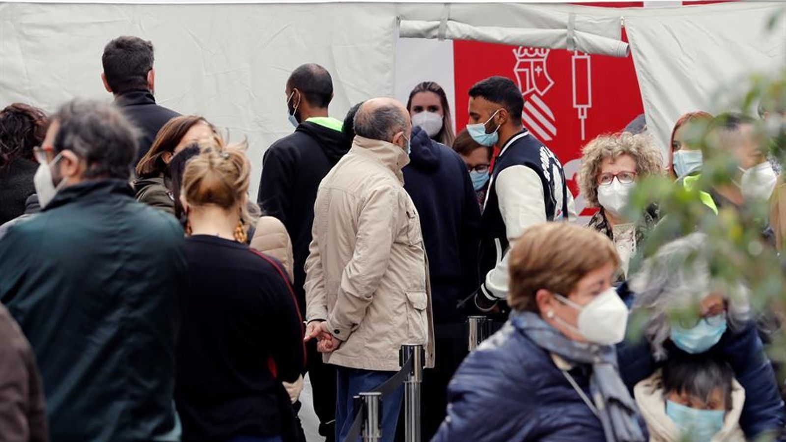 Diverses persones fan cua en el punt de vacunació habilitat a la plaça de Manises, de València