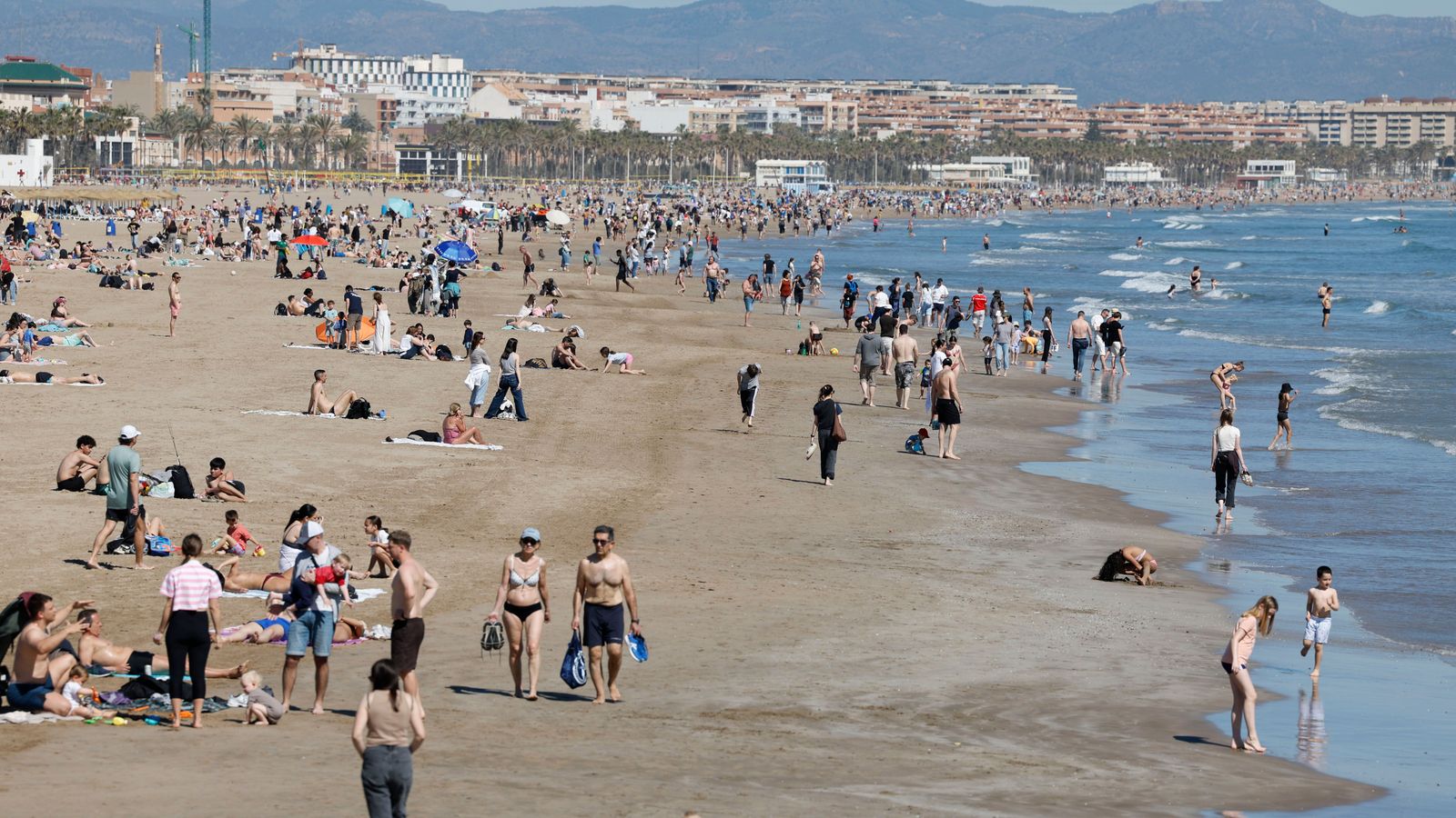 Desenes de turistes gaudint de la platja, a València, durant el Dissabte Sant