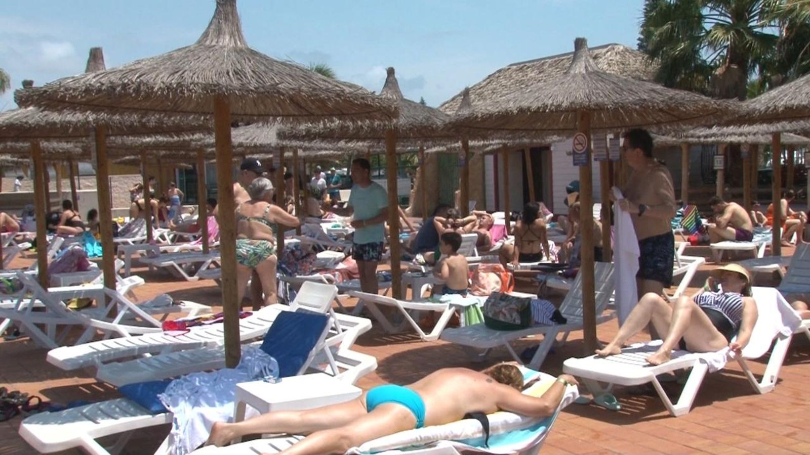 Turistes prenen el sol a la piscina d'un hotel