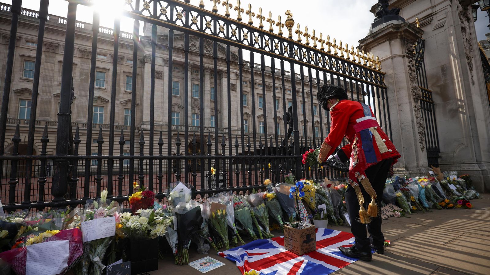 Un home diposita flors davant del Palau de Buckingham  per la mort del Duc d'Edimburg