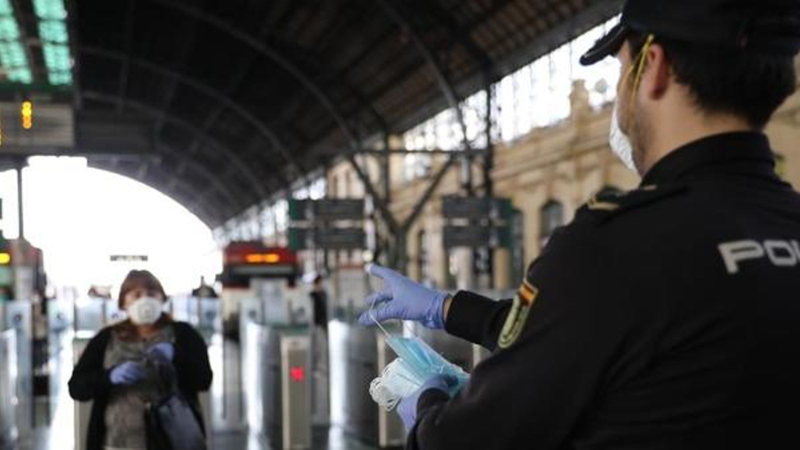 Un agent de la Policia Nacional reparteix mascaretes en l'estació del Nord de València, aquest dilluns