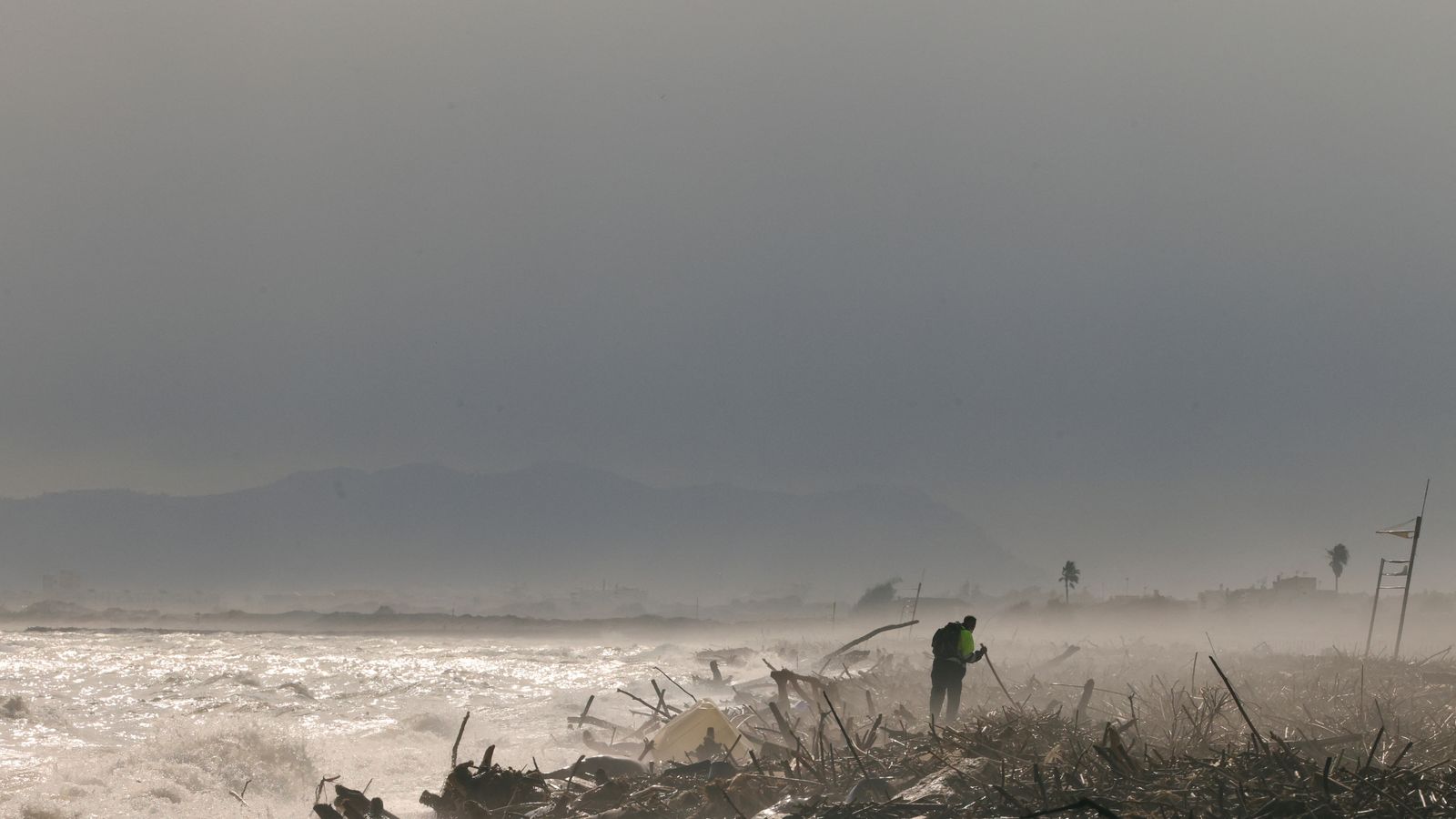 Un voluntari camina buscant víctimes de la destrucció a la vora de la platja del Saler