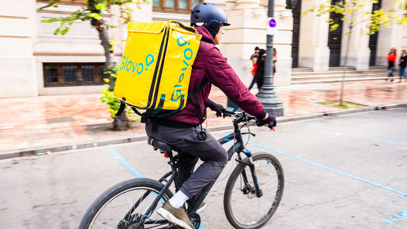 Un repartidor de Glovo avança en bicicleta per la plaça de l'Ajuntament de València en una imatge d'arxiu