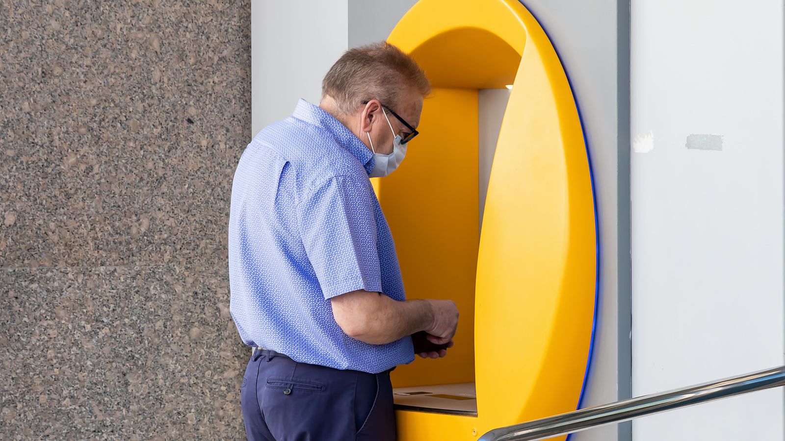 Imatge d'arxiu d'un home traent diners d'un caixer