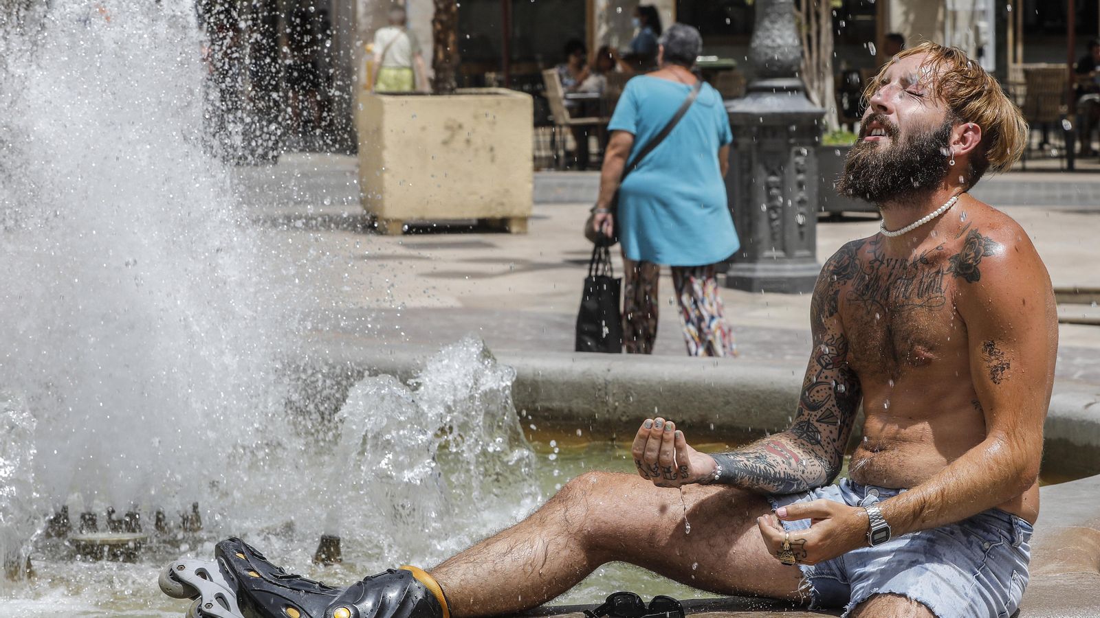 Un home es refresca en una font del centre de València per a suportar les altes temperatures en una imatge d'arxiu