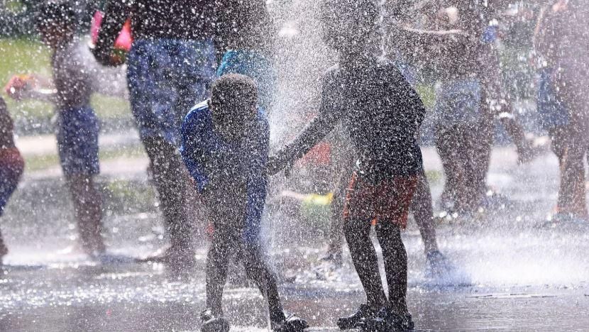 Dos xiquets es refresquen en una font / EFE