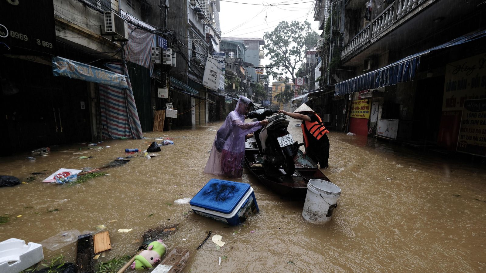Dos persones en una barca carregada amb una motocicleta a través de les aigües inundades, a Hanoi, Vietnam