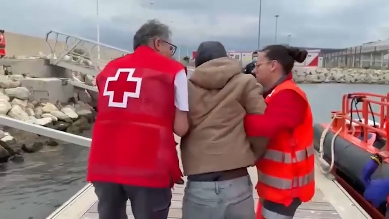 Voluntaris de Creu Roja ajuden una de les persones rescatades a baixar de la pastera