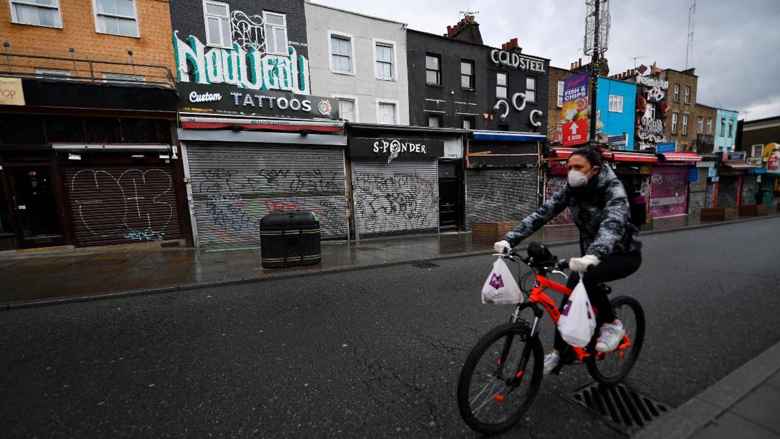 Una ciclista passa per davant dels comerços tancats al carrer de Camden, a Londres