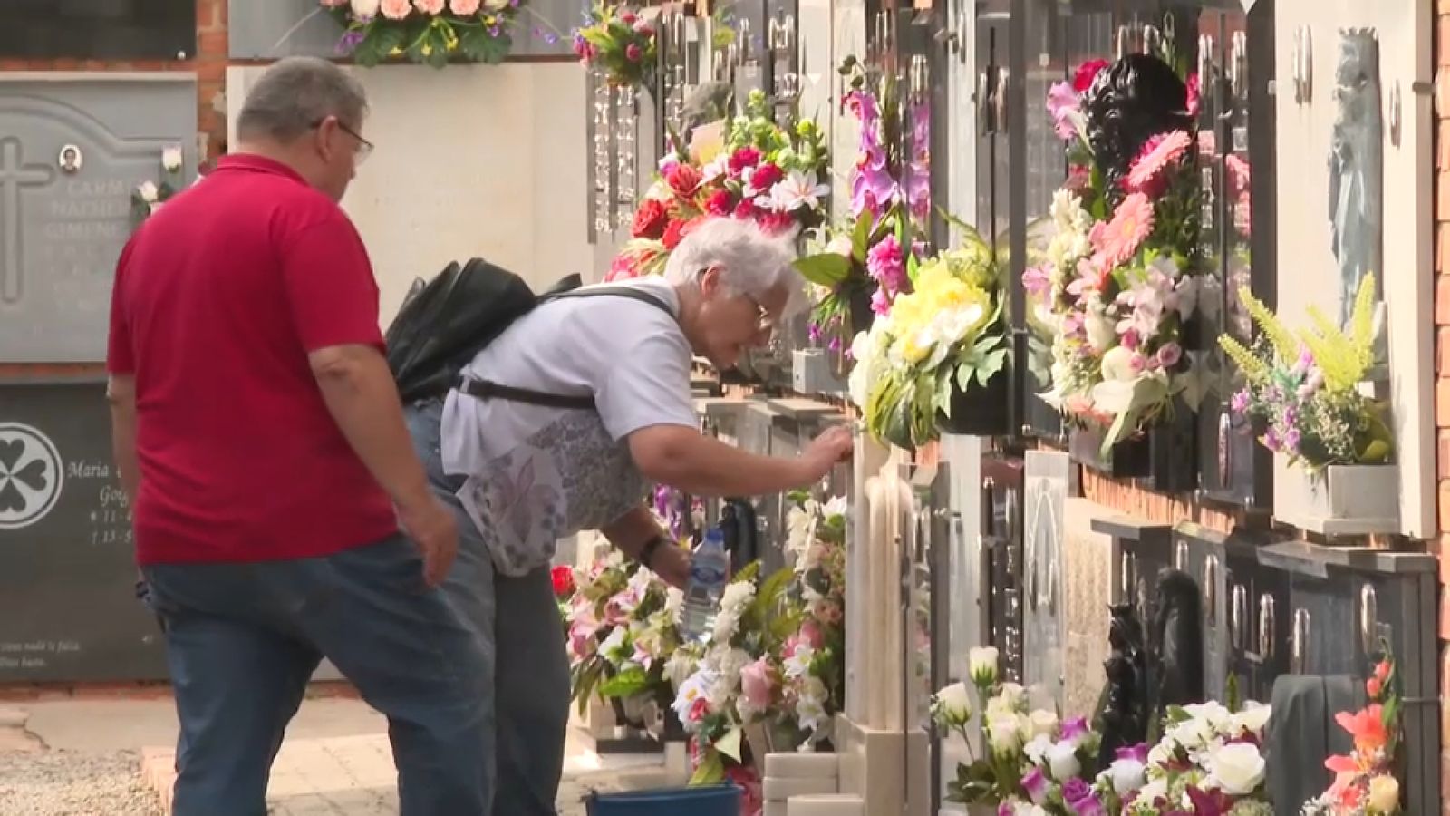 Una parella neteja una de les làpides del cementeri de Sagunt aquest dilluns