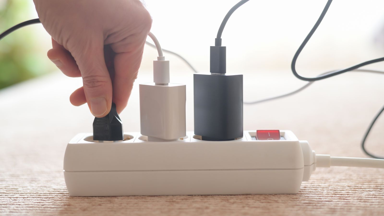 Una persona connecta endolls a una regleta (arxiu)