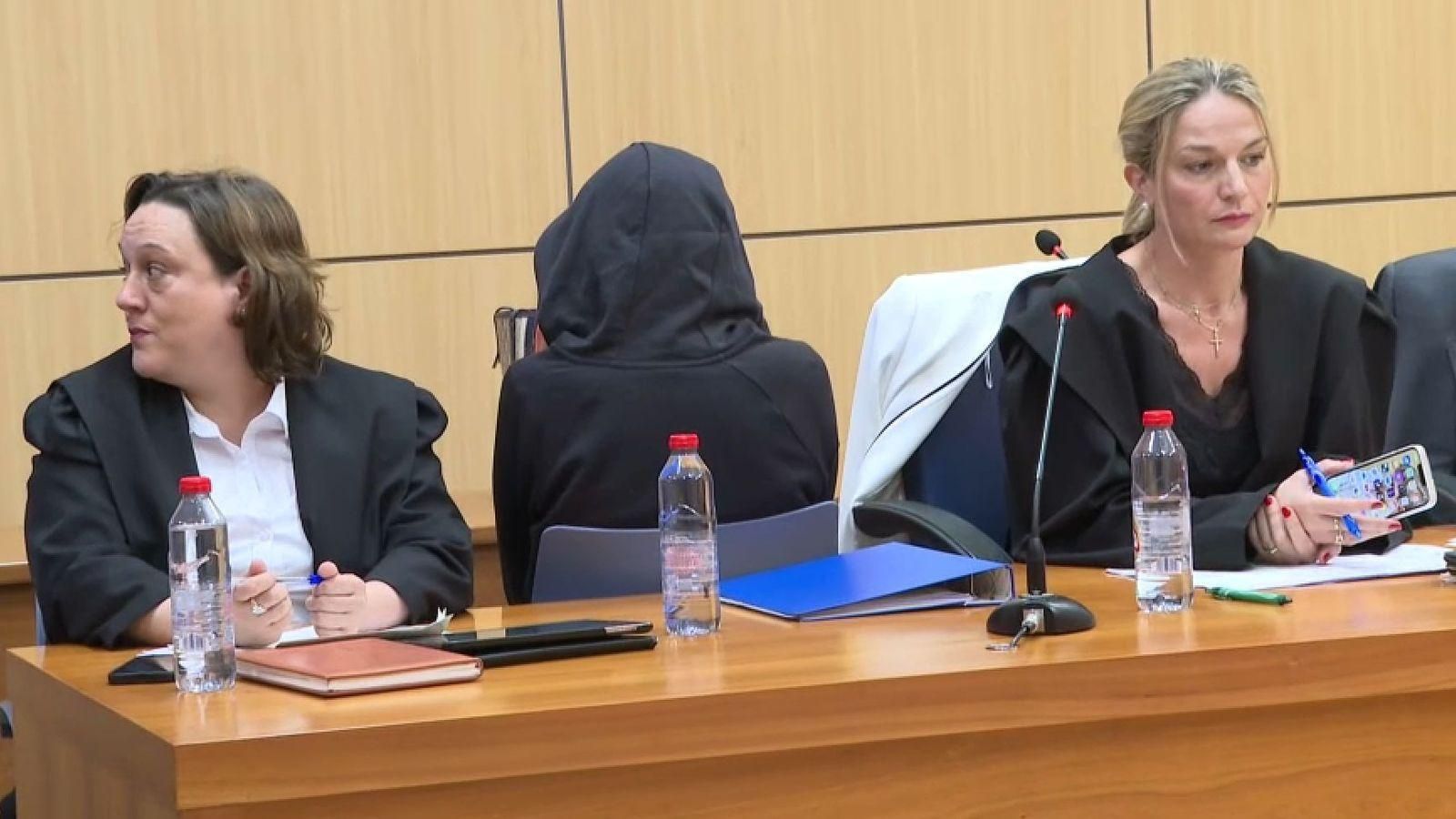 L'assassina confessa, amb el rostre ocult amb una caputxa, al costat de les seues advocades