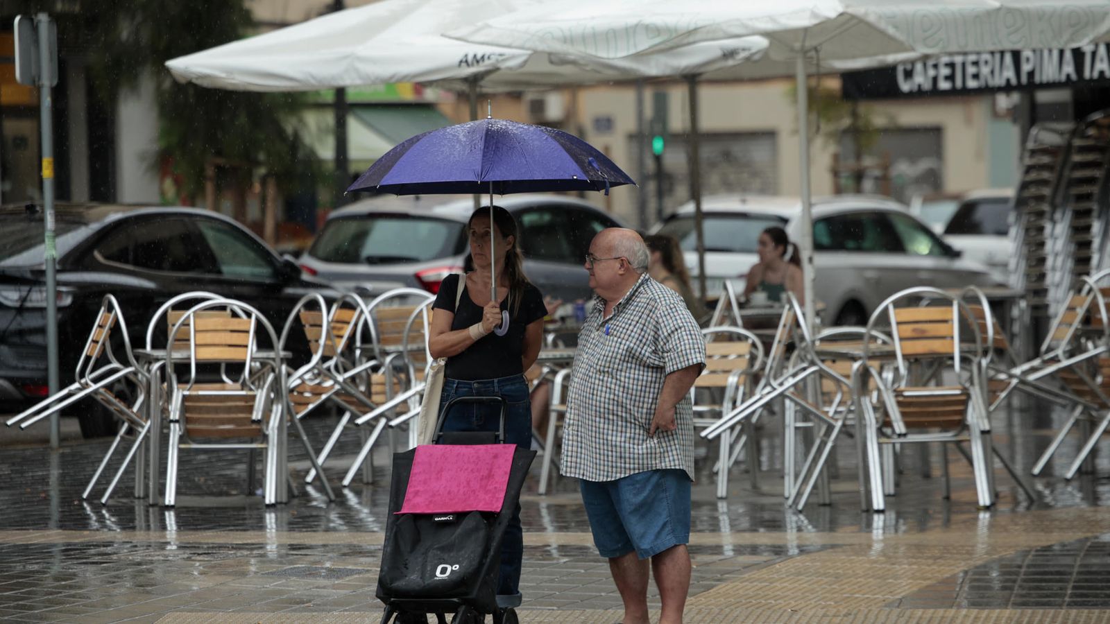 Dos persones es protegixen de l'aigua amb un paraigua