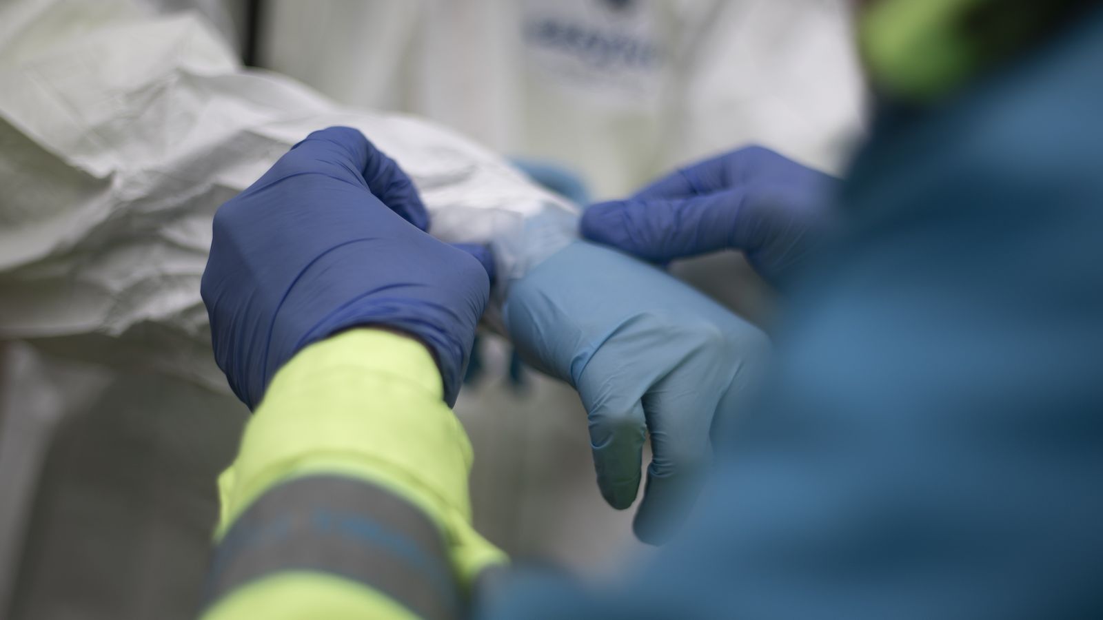 Un sanitari coloca un guant a un altre per a evitar el contacte i reduir riscos al lloc de treball