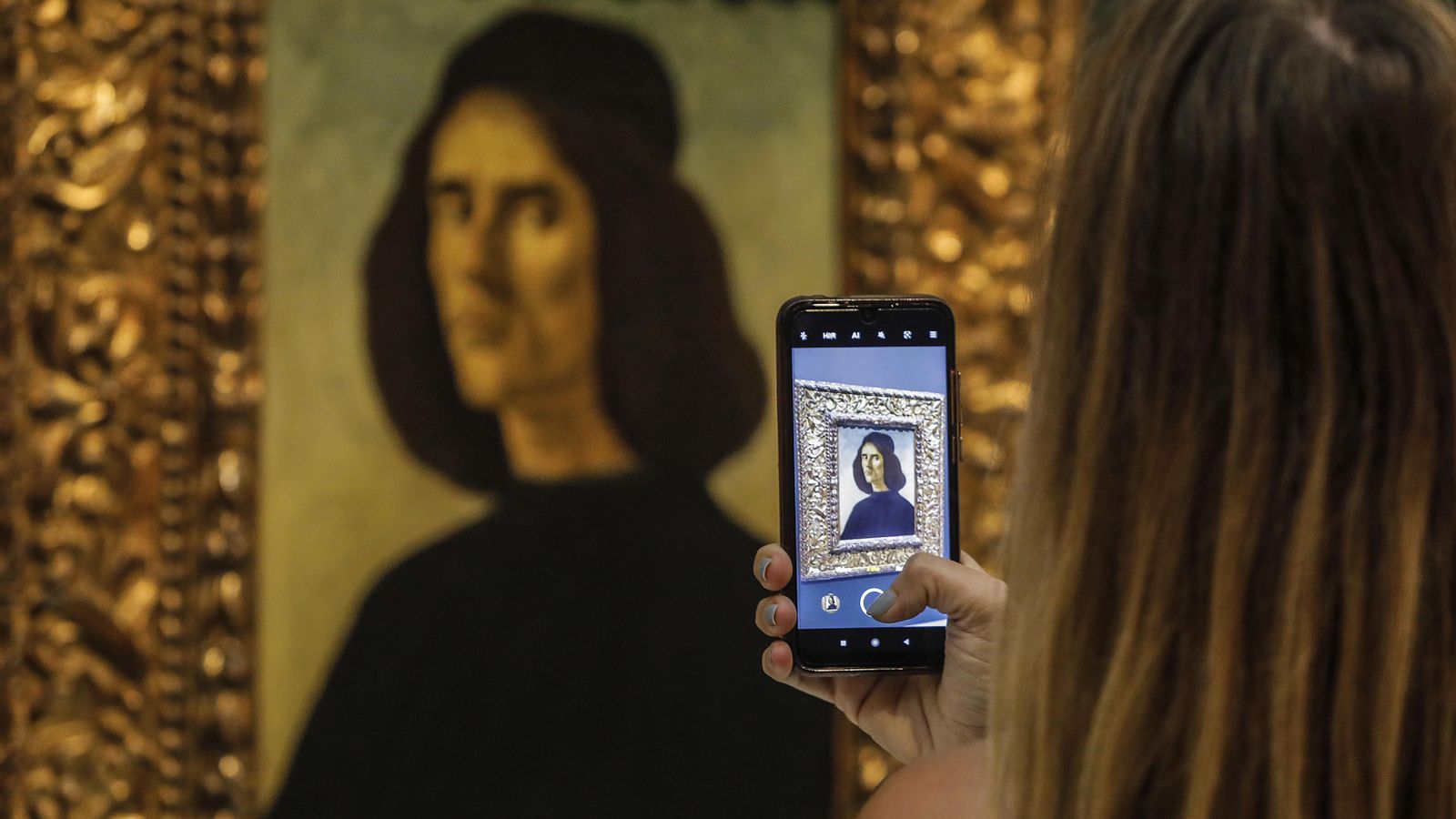Una visitant fotografia el retrata de Botticelli que, des d'aquest dimarts, es pot observar al Museu de Belles Arts de València