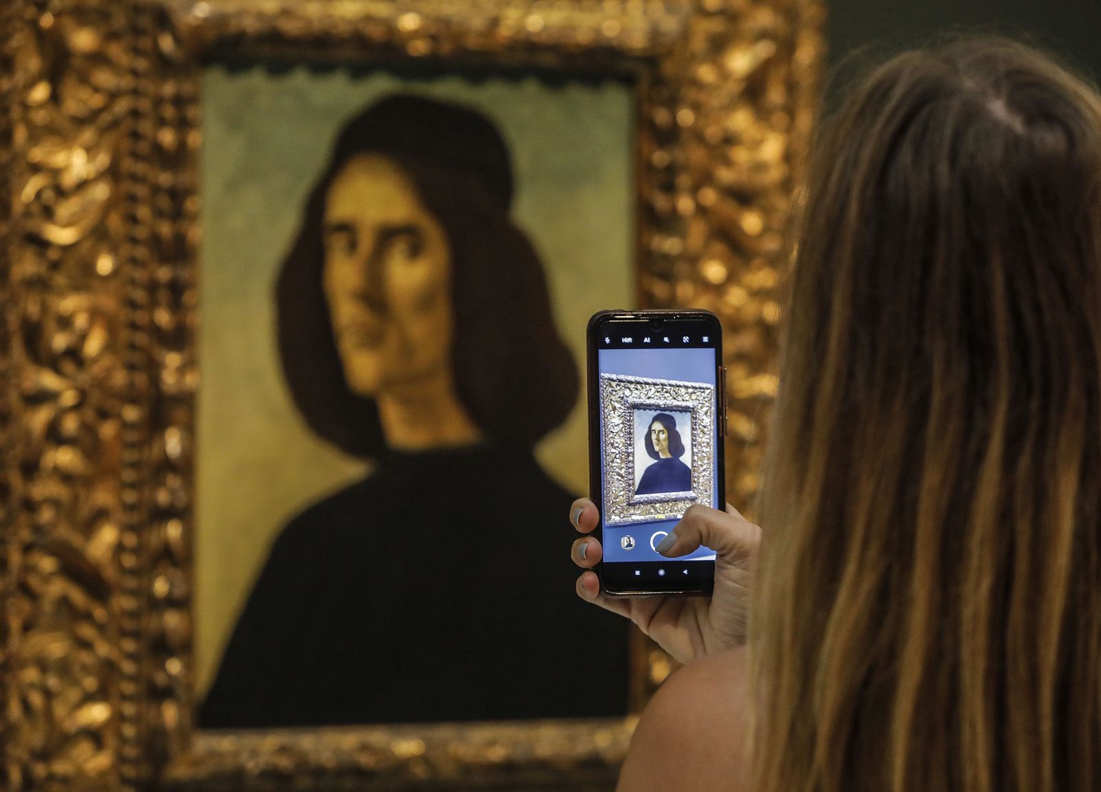 Una visitant fotografia el retrata de Botticelli que, des d'aquest dimarts, es pot observar al Museu de Belles Arts de València