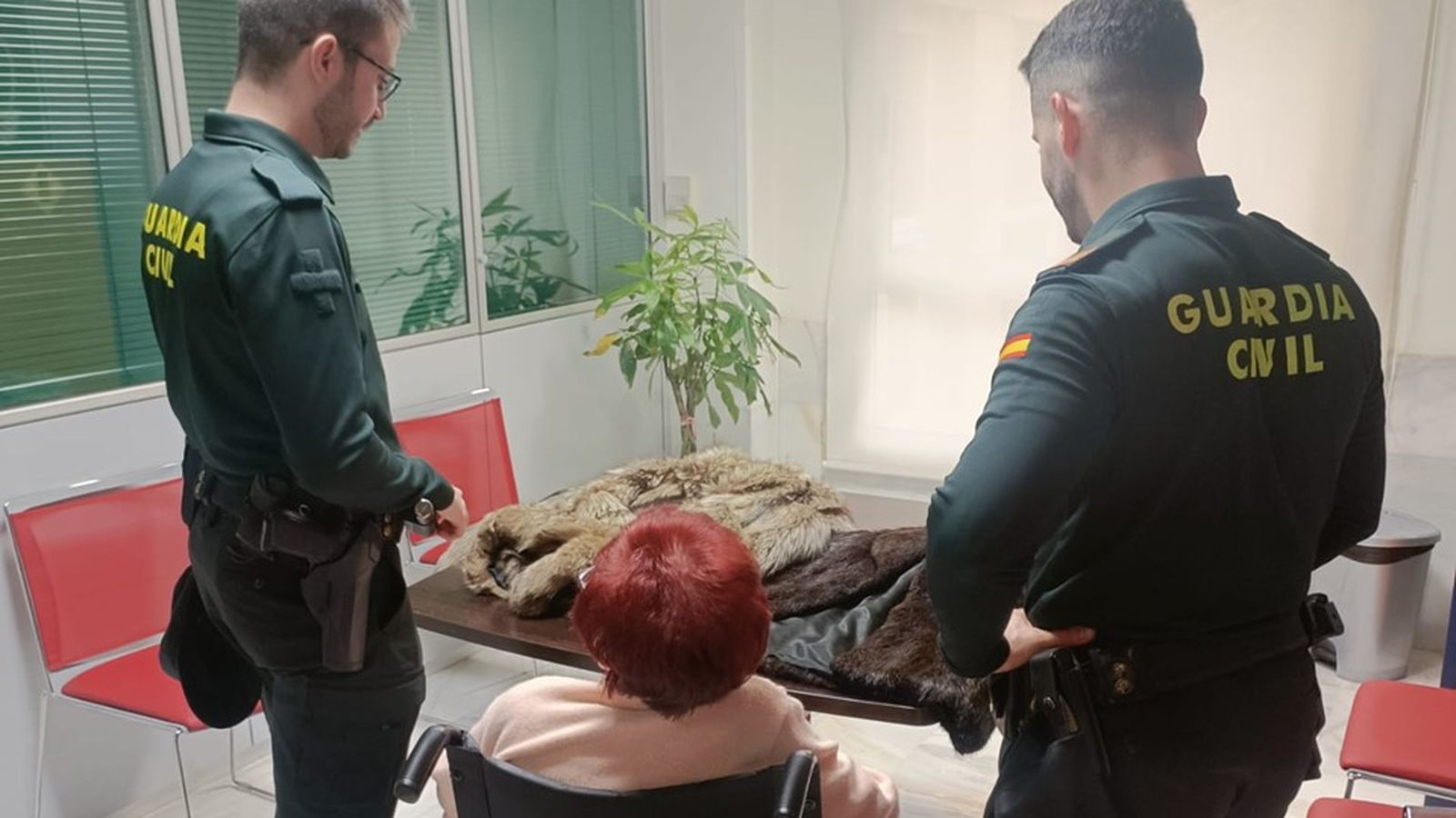 Dos agents de la Guàrdia Civil amb la víctima de l'estafa i els dos abrics encautats