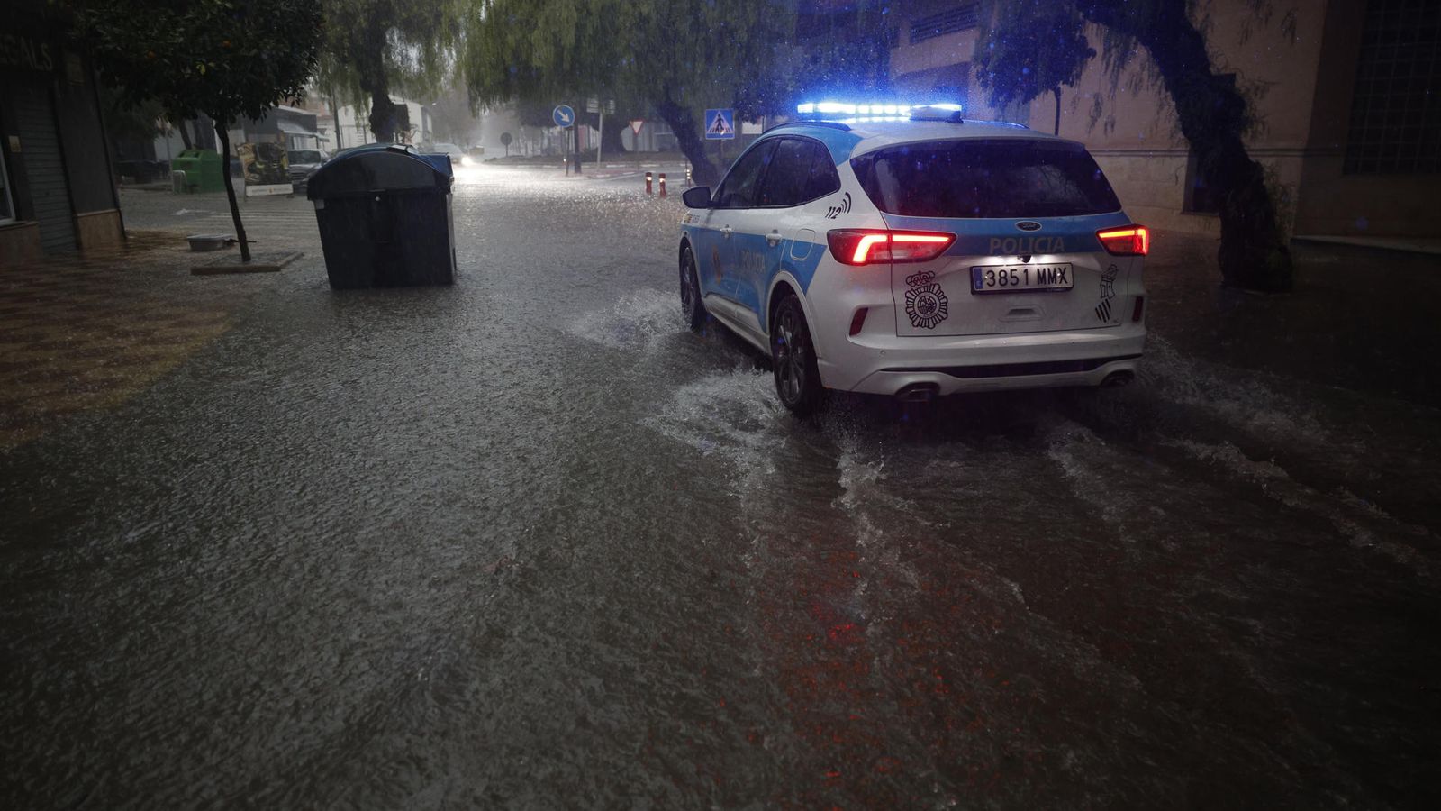 Un vehicle policial circula per un carrer negat a la localitat de l’Alcúdia (València) este diumenge.