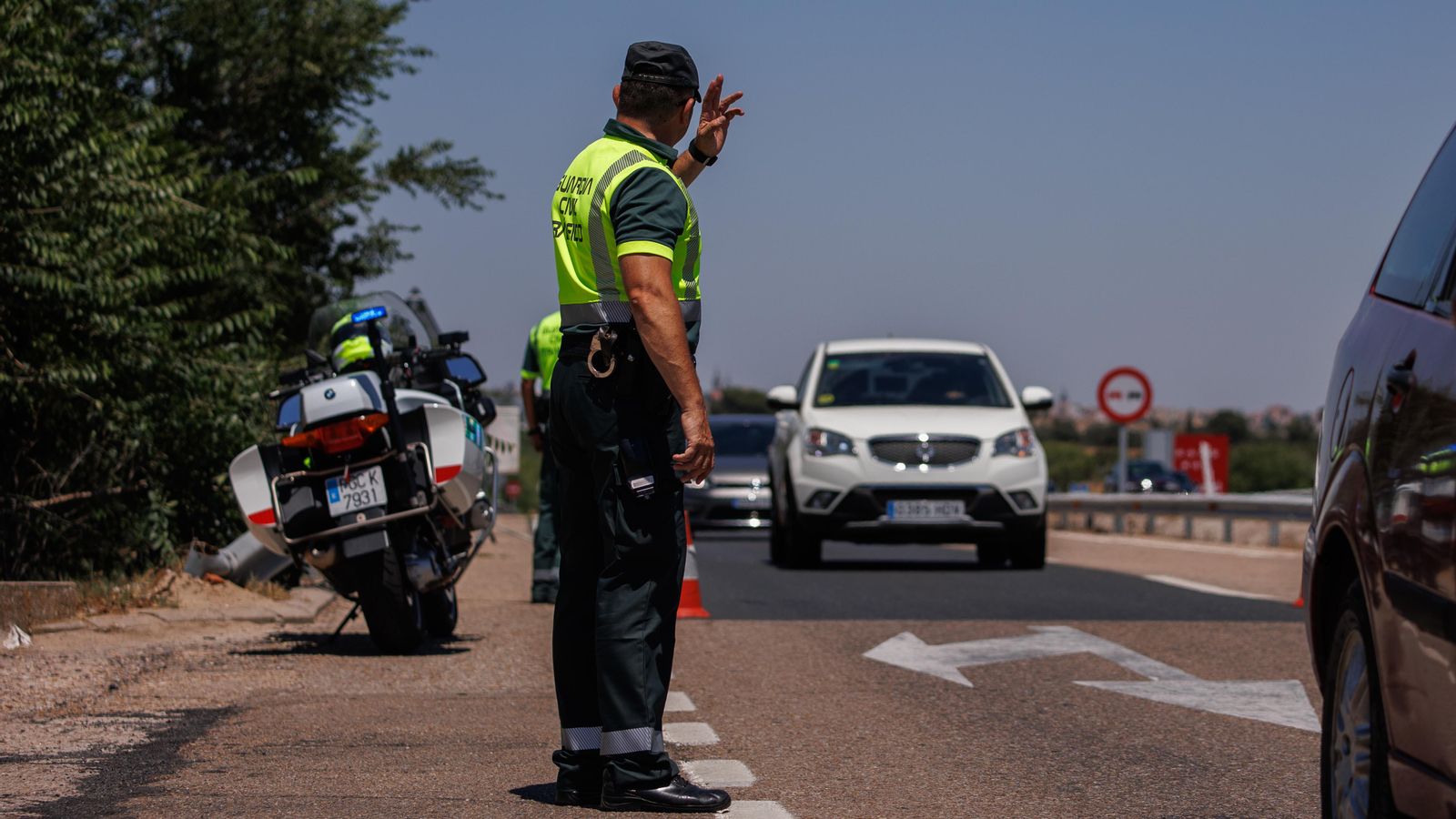 Un agent de la Guàrdia Civil per a a un vehicle durant un control en l'autovia A-5