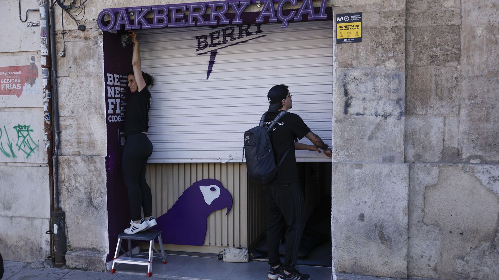 Dos treballadors baixen la persiana del seu negoci a València, este dilluns, amb motiu de l'apagada de subministrament elèctric