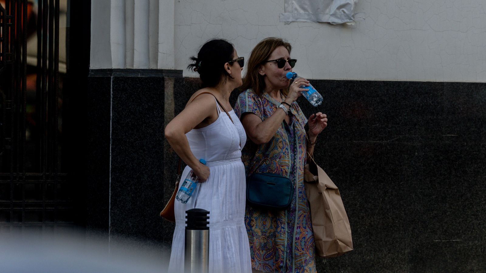 Dos dones beuen aigua al carrer davant de la calor