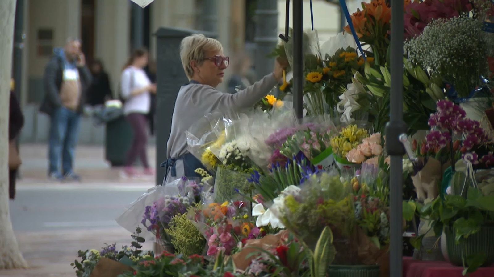 Una florista de la plaça de l'Ajuntament de València adreça la seua parada