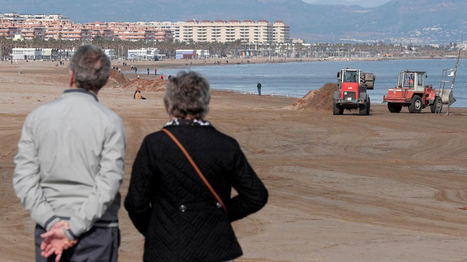 Una parella contempla la platja de la Malva-rosa durant les tasques de neteja i reparació aquest 27 de gener
