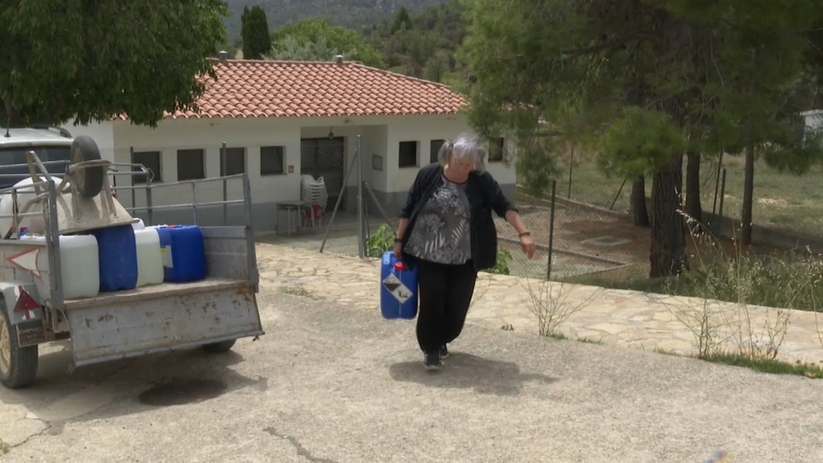 Veïna de Villores carregant garrafes amb aigua de la piscina municipal