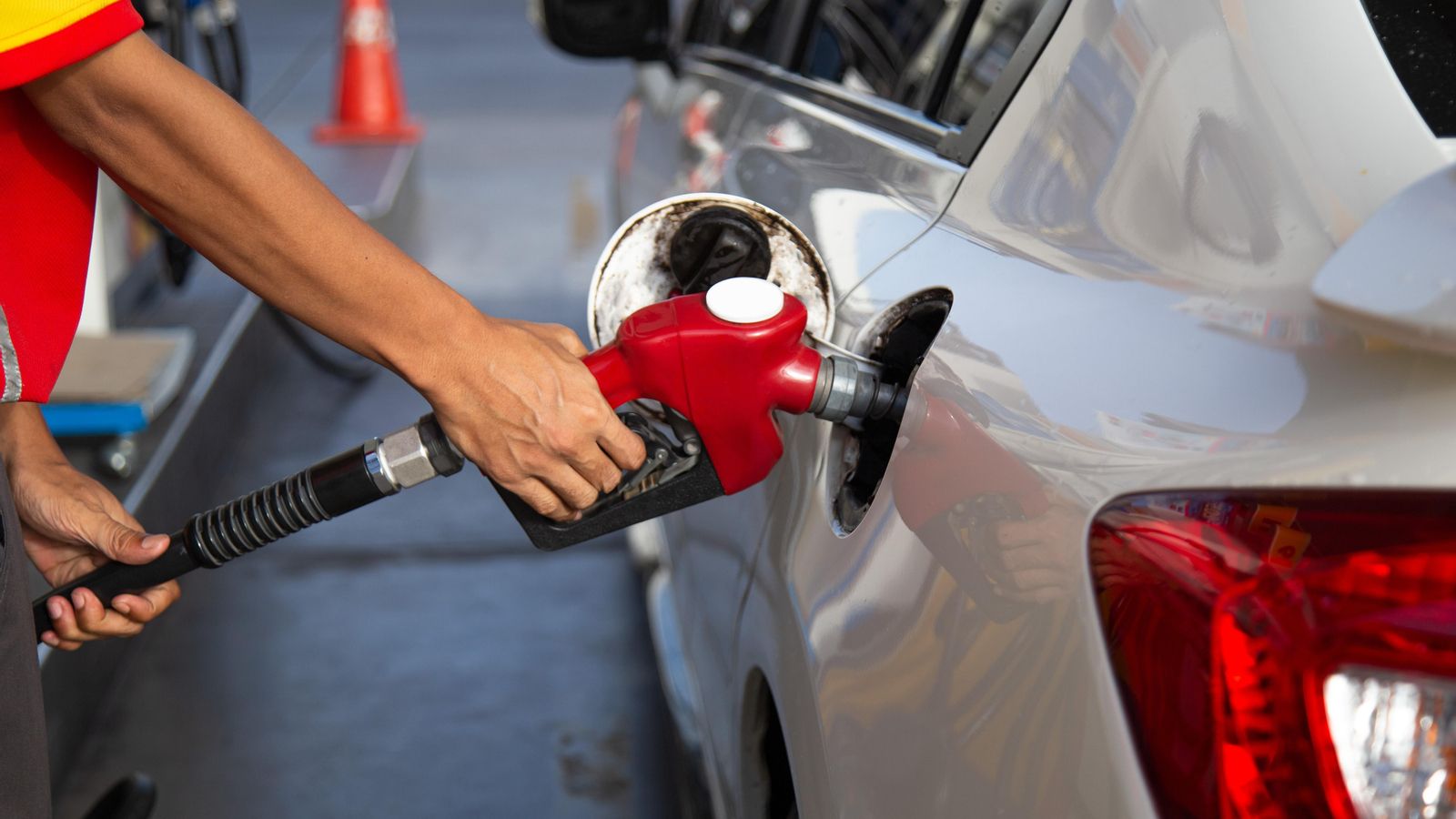 Un operari ompli el depòsit d'un cotxe amb combustible