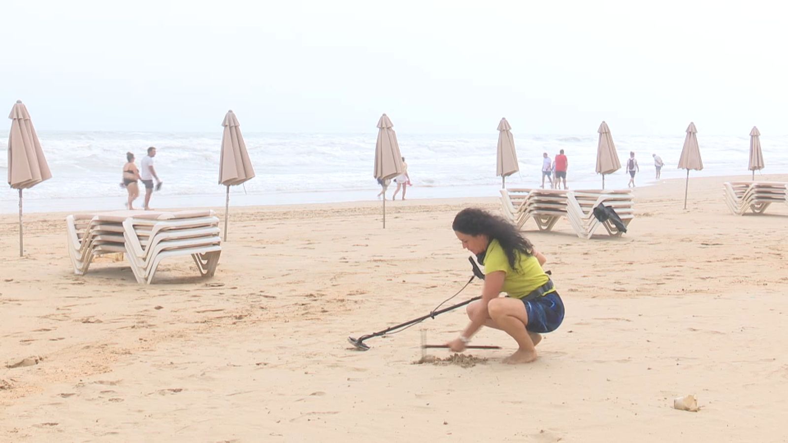 Isabel escarba amb els seus artilugis a la platja de Gandia