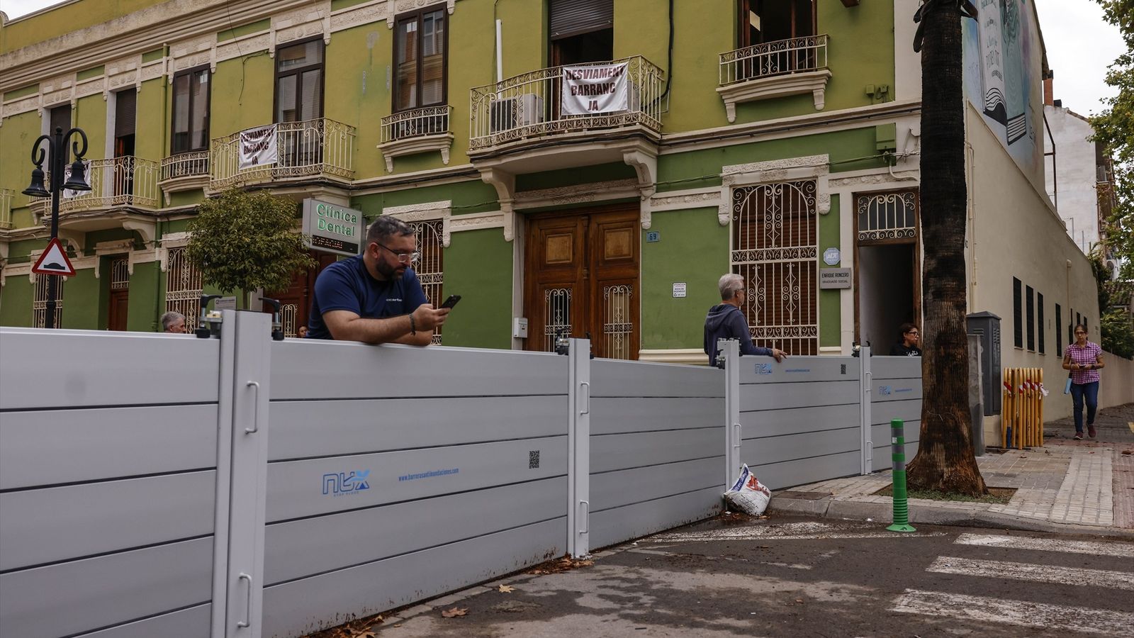 Dos homes conversen recolzats en una de les barreres instal·lades a Aldaia pel desbordament del barranc de La Saleta