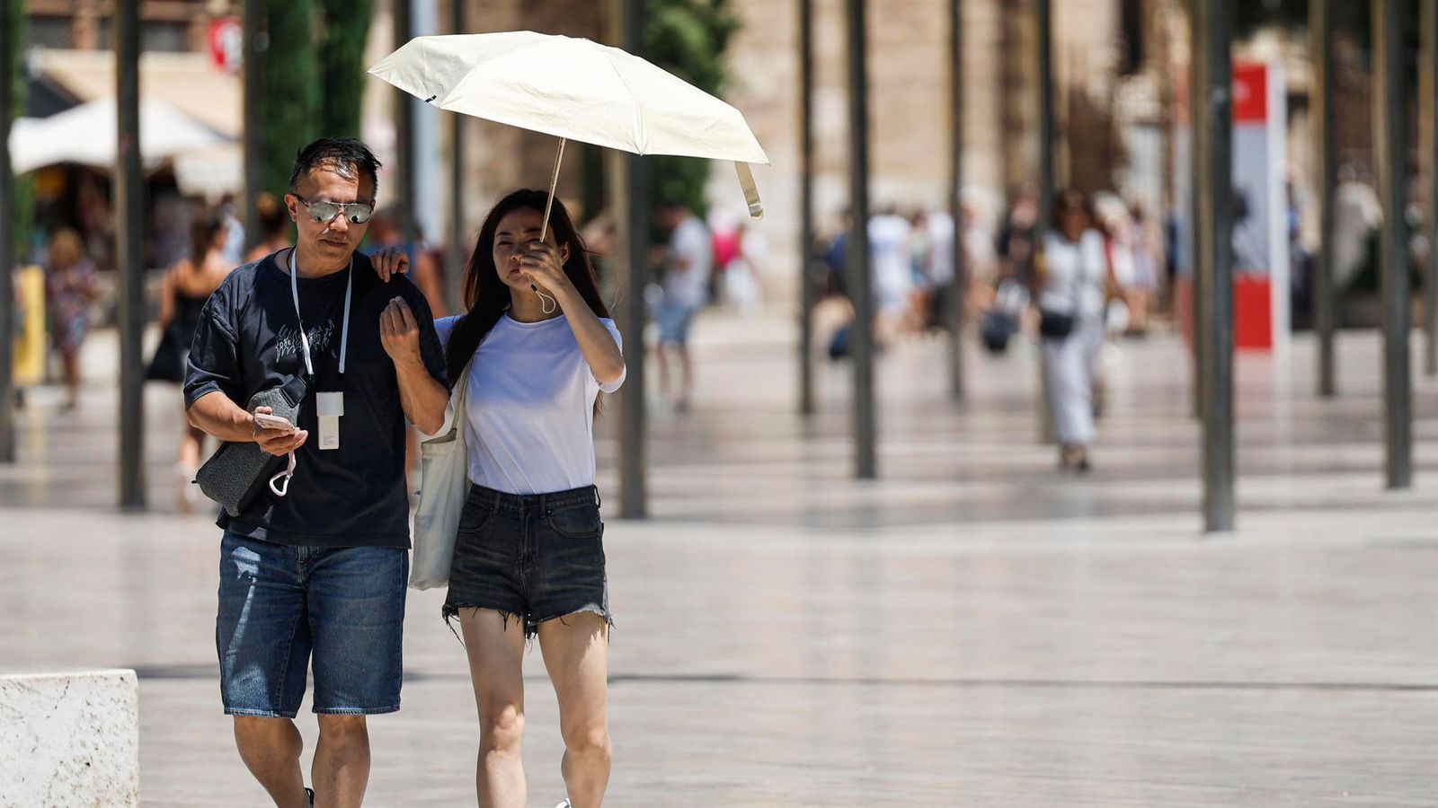 Dos persones es protegixen del sol amb un paraigua, este dilluns a València