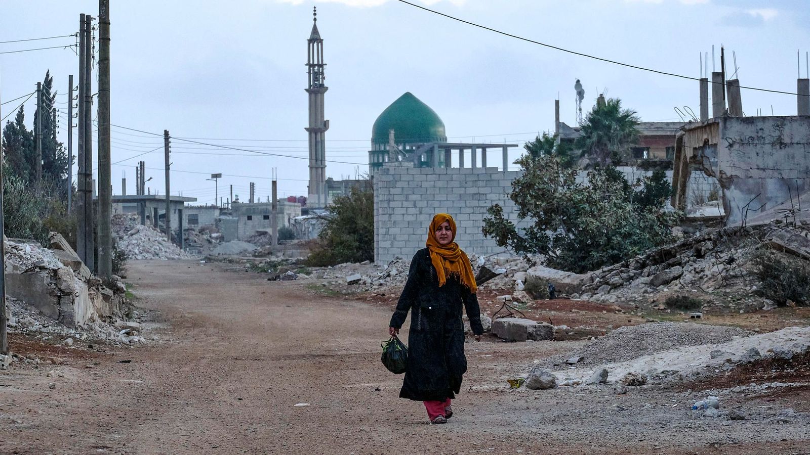Una dona avança entre les runes que han deixat els tretze anys d'enfrontaments que va viure Síria