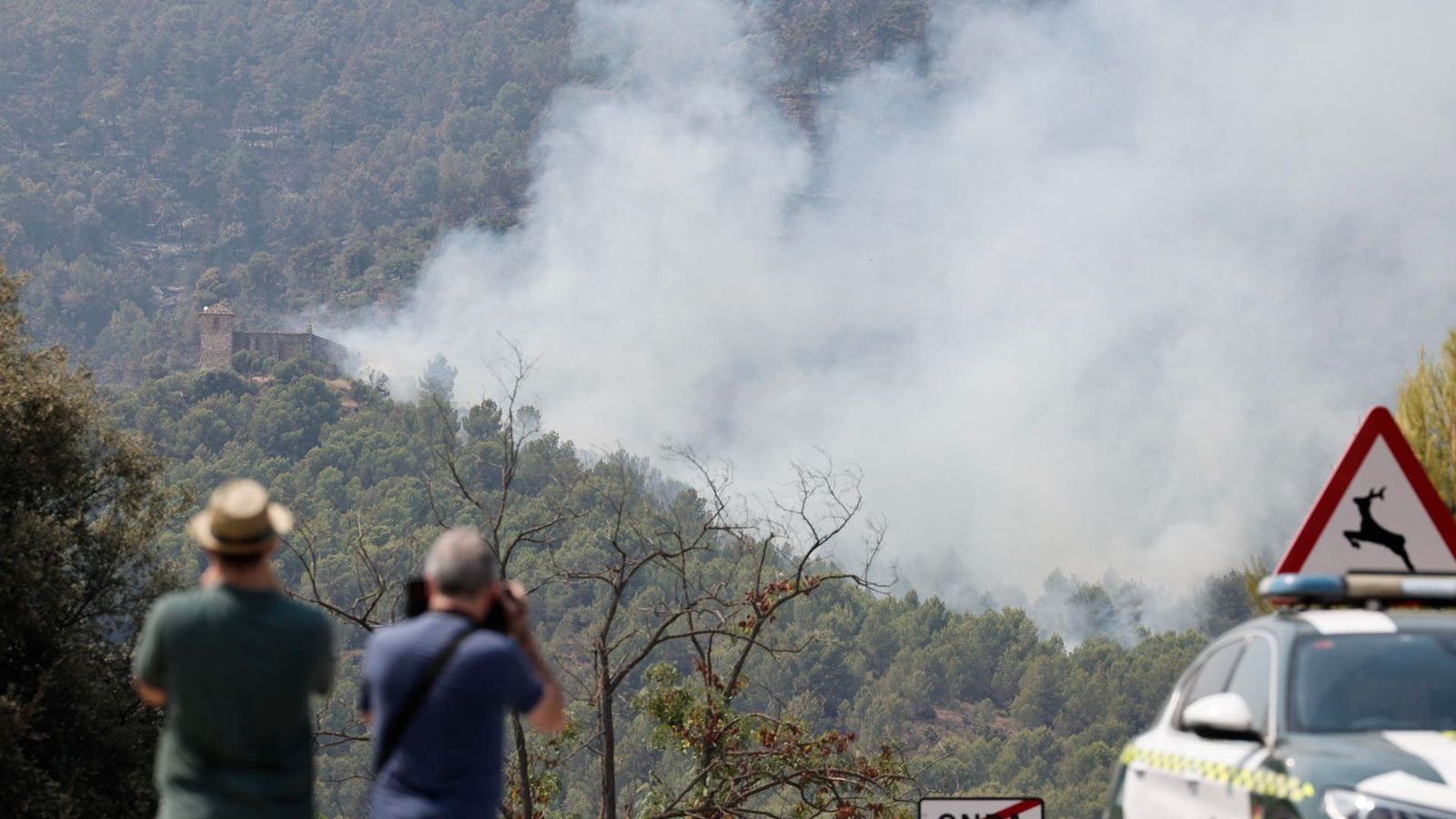 Dos homes seguixen l'avanç del foc que, des de dissabte, crema la serra d'Espadà