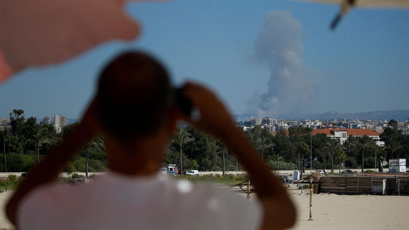 Un home contempla una columna de fum des del Líban després de l'impacte d'un projectil israelià