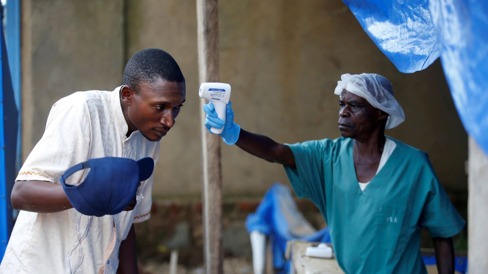 Un sanitari mesura la temperatura d'un home a l'entrada d'un centre, a la República Democràtica del Congo