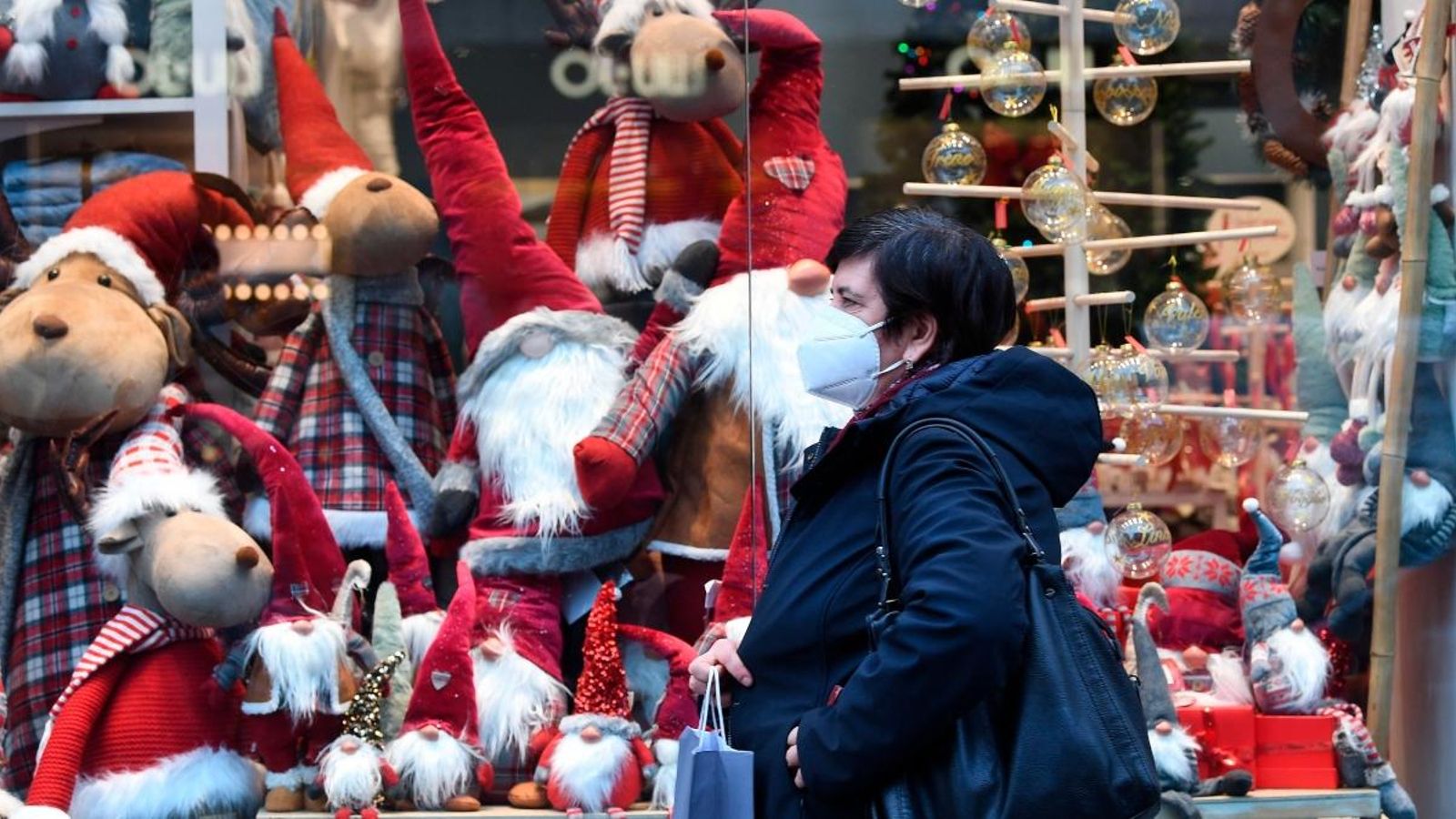 Una dona amb mascareta camina davant d'un aparador nadalenc d'una botiga a Milà, aquest dilluns