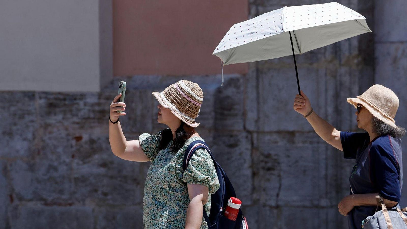 Dos dones es protegeixen del sol mentre fan turisme per la ciutat de València Dos dos es protegeixen del sol mentre fan turisme per la ciutat de València