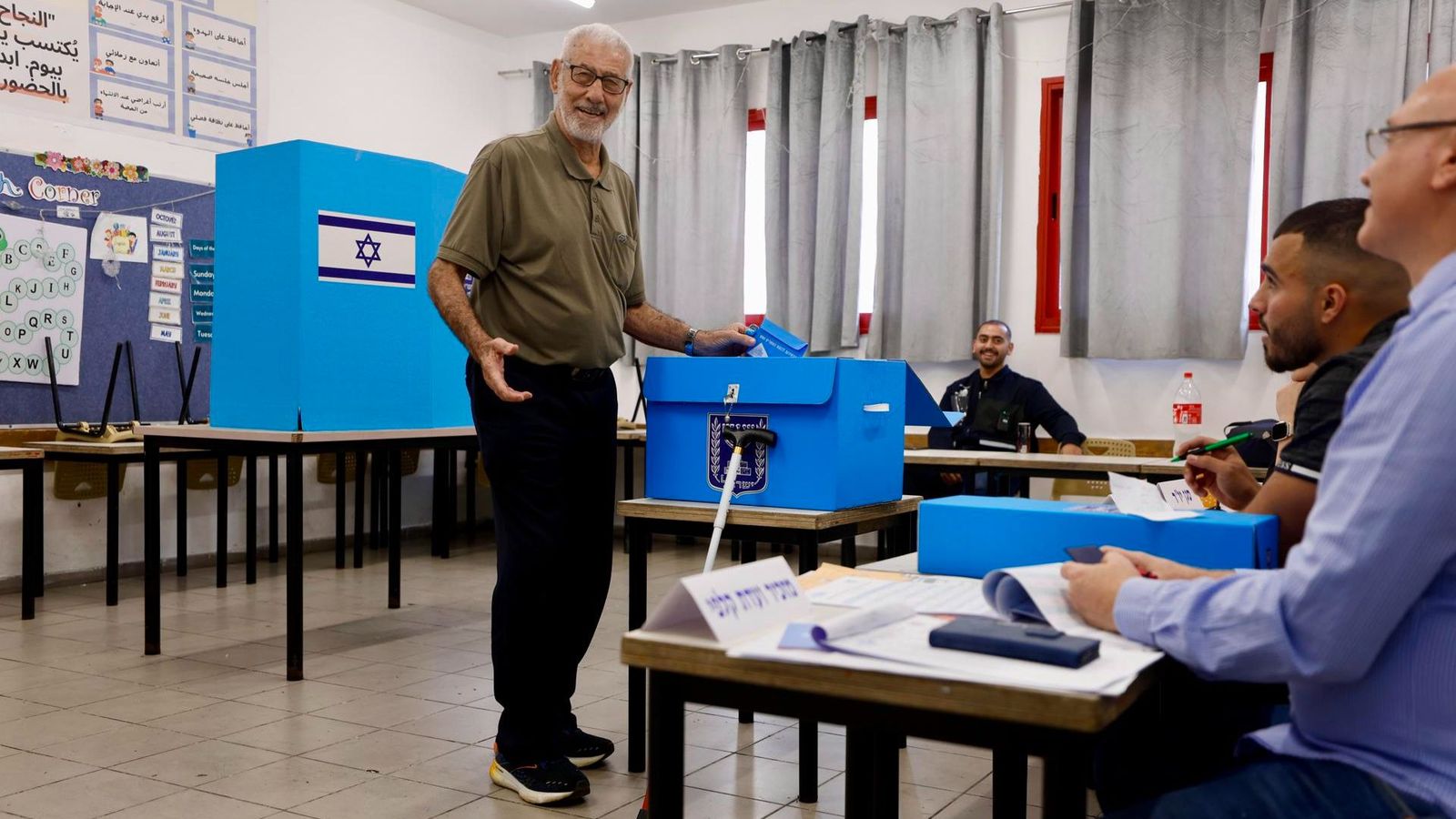Un ciutadà deposita el seu vot en la urna d'un col·legi electoral d'Israel sota la mirada dels membres de la mesa electoral