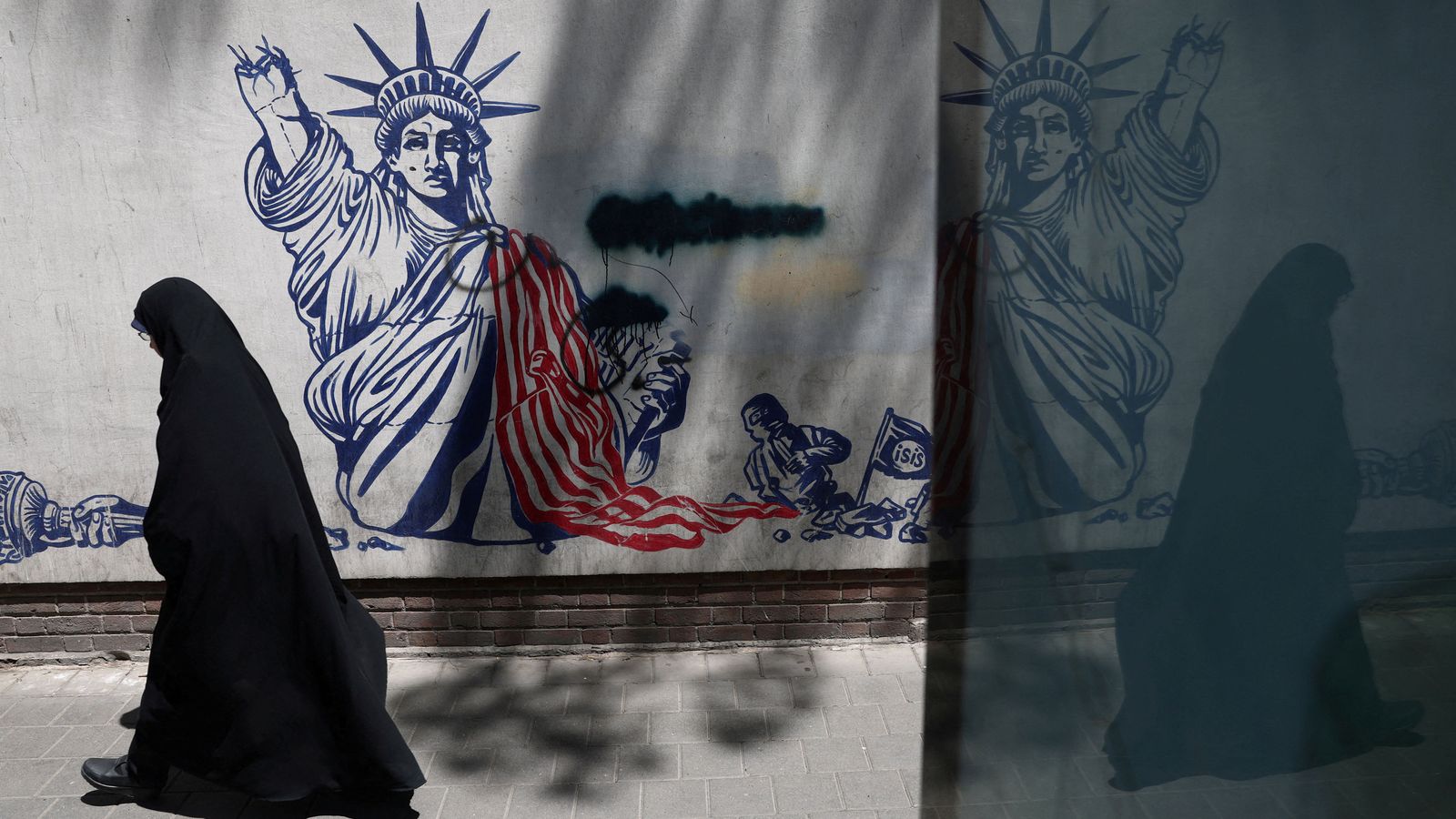 Una dona camina al costat d'un mural en Teheran