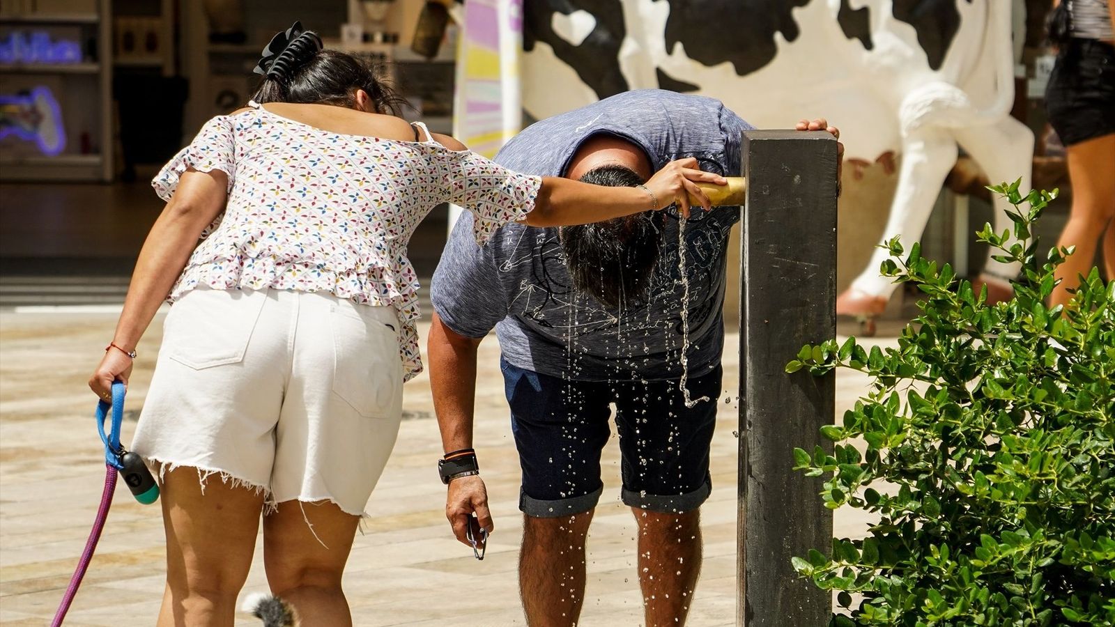 Un home es refreda el cap davall d'una font, a València