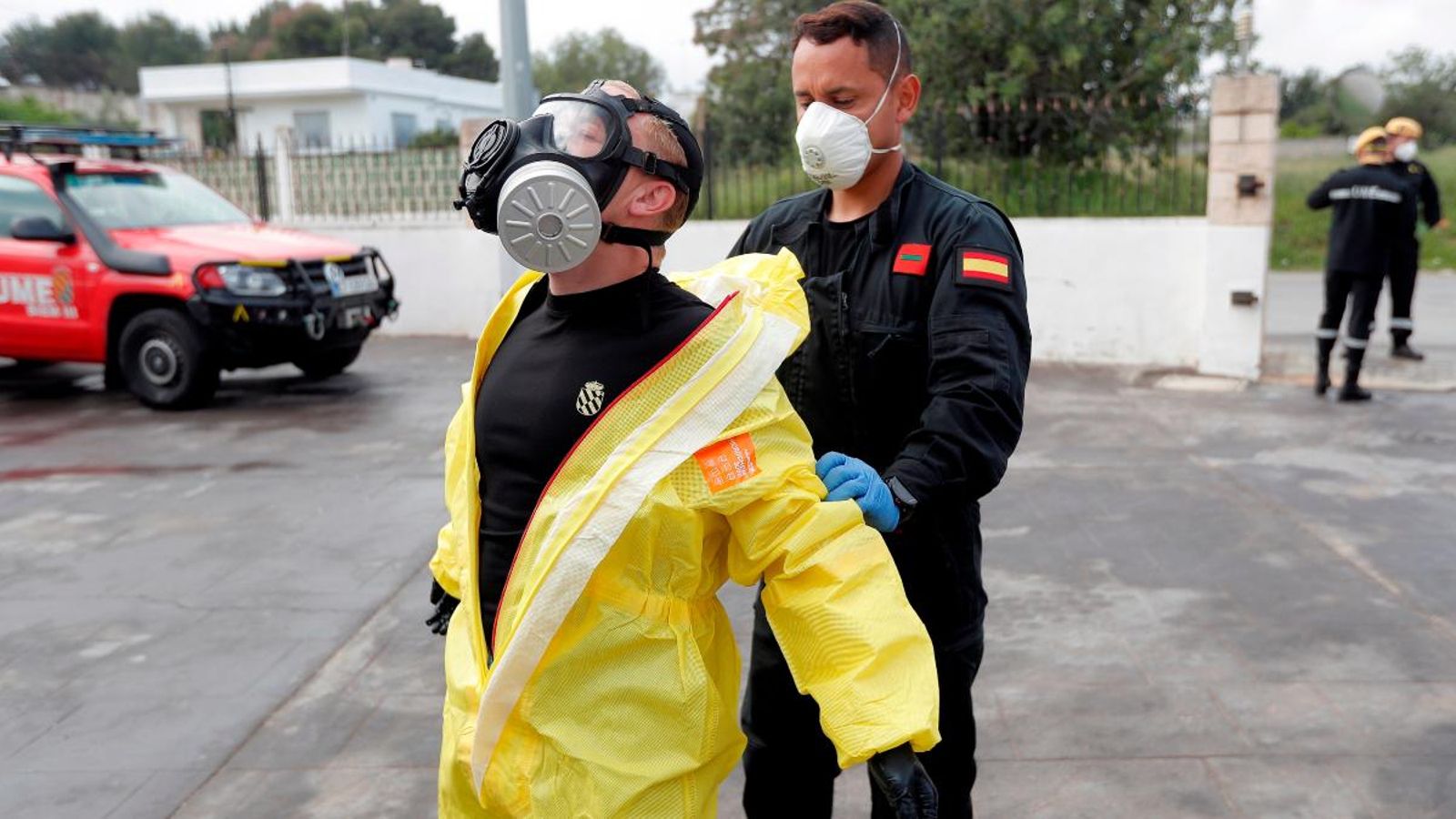 Un membre de la UME ajuda al seu company a llevar-se la granota de protecció després de desinfectar una residència d’ancians