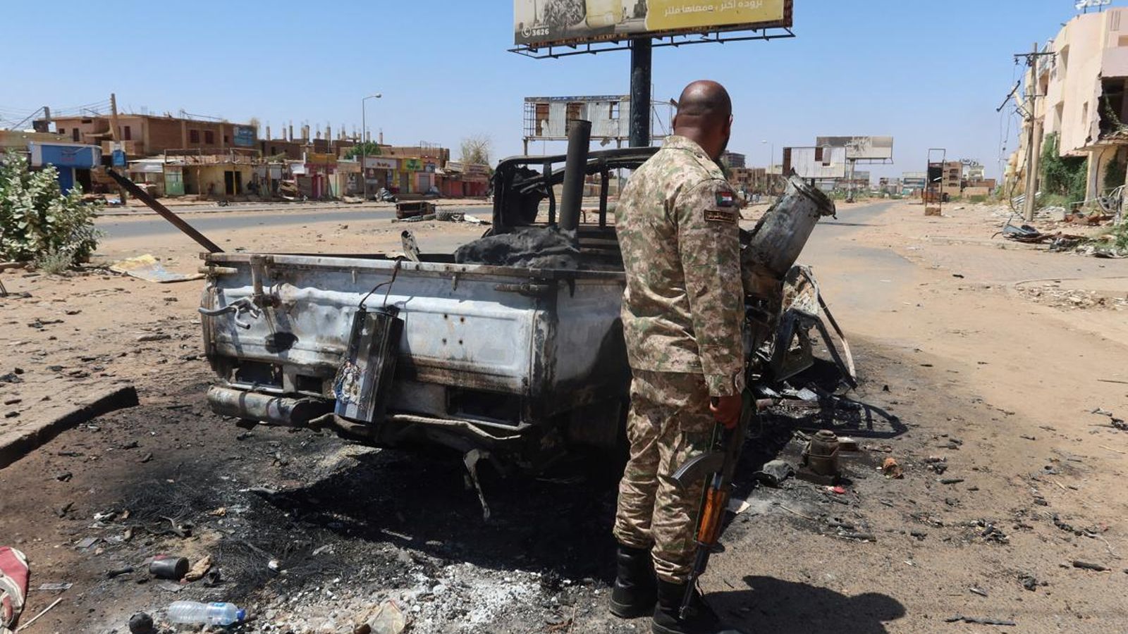 Un soldat de l'exèrcit sudanés al costat d'un vehicle de combat destruït en l'estat de Khartum