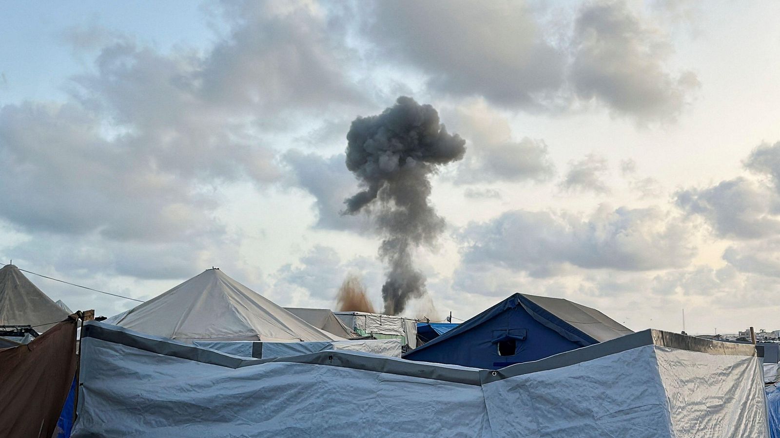 Una columna de fum producte d'un atac isrelià vista des de les tendes per a refugiats de Khan Yunis