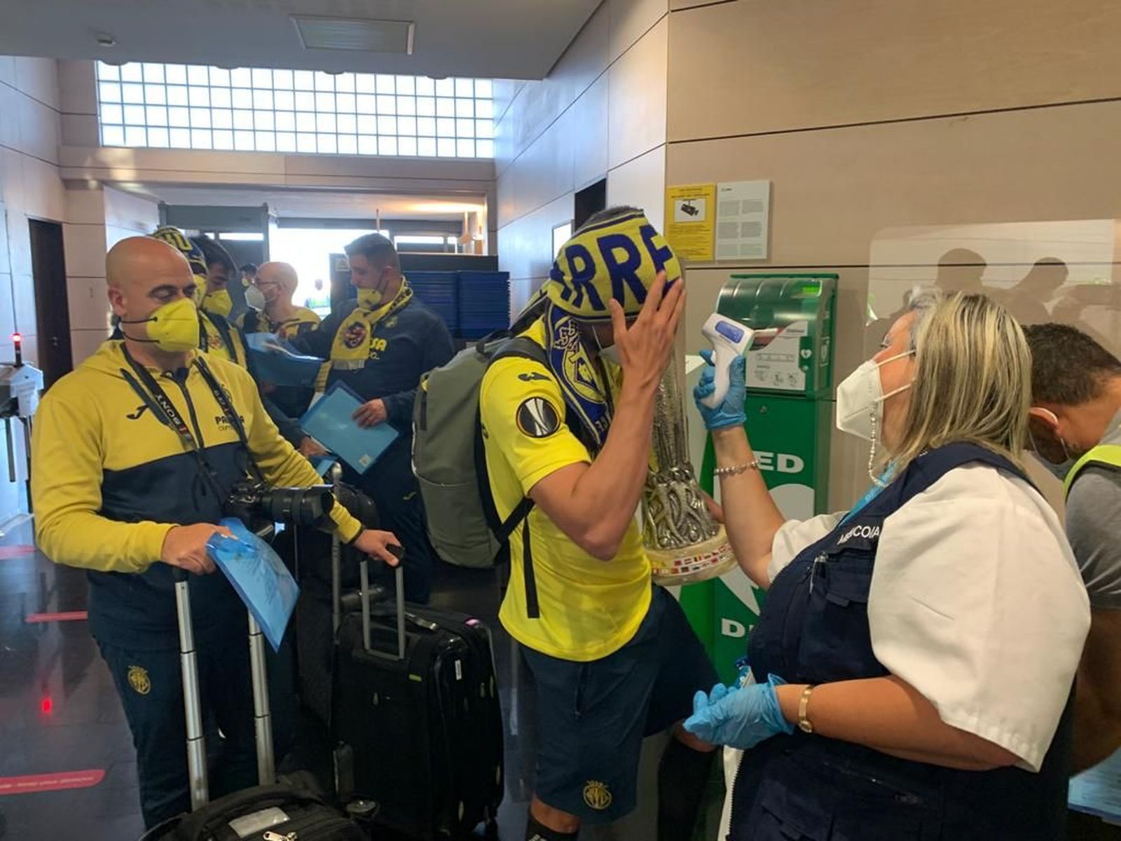 Una treballadora d'Aena pren la temperatura a Mario Gaspar amb la copa de l'Europa League