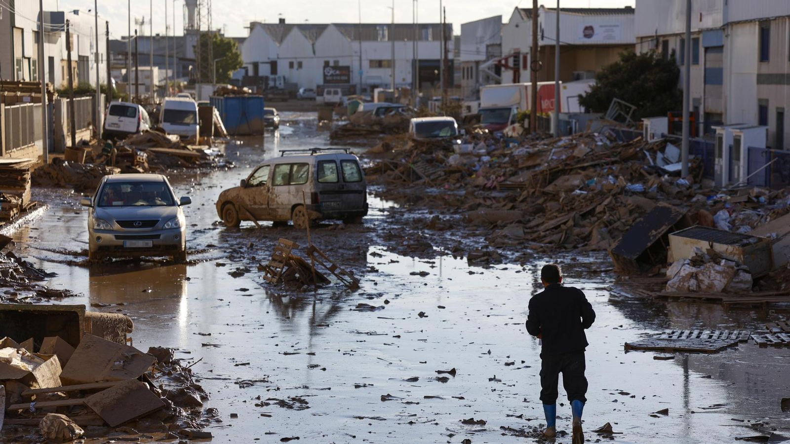 Un vianant avança entre les deixalles que s'acumulen en un dels carrers del polígon de Catarroja
