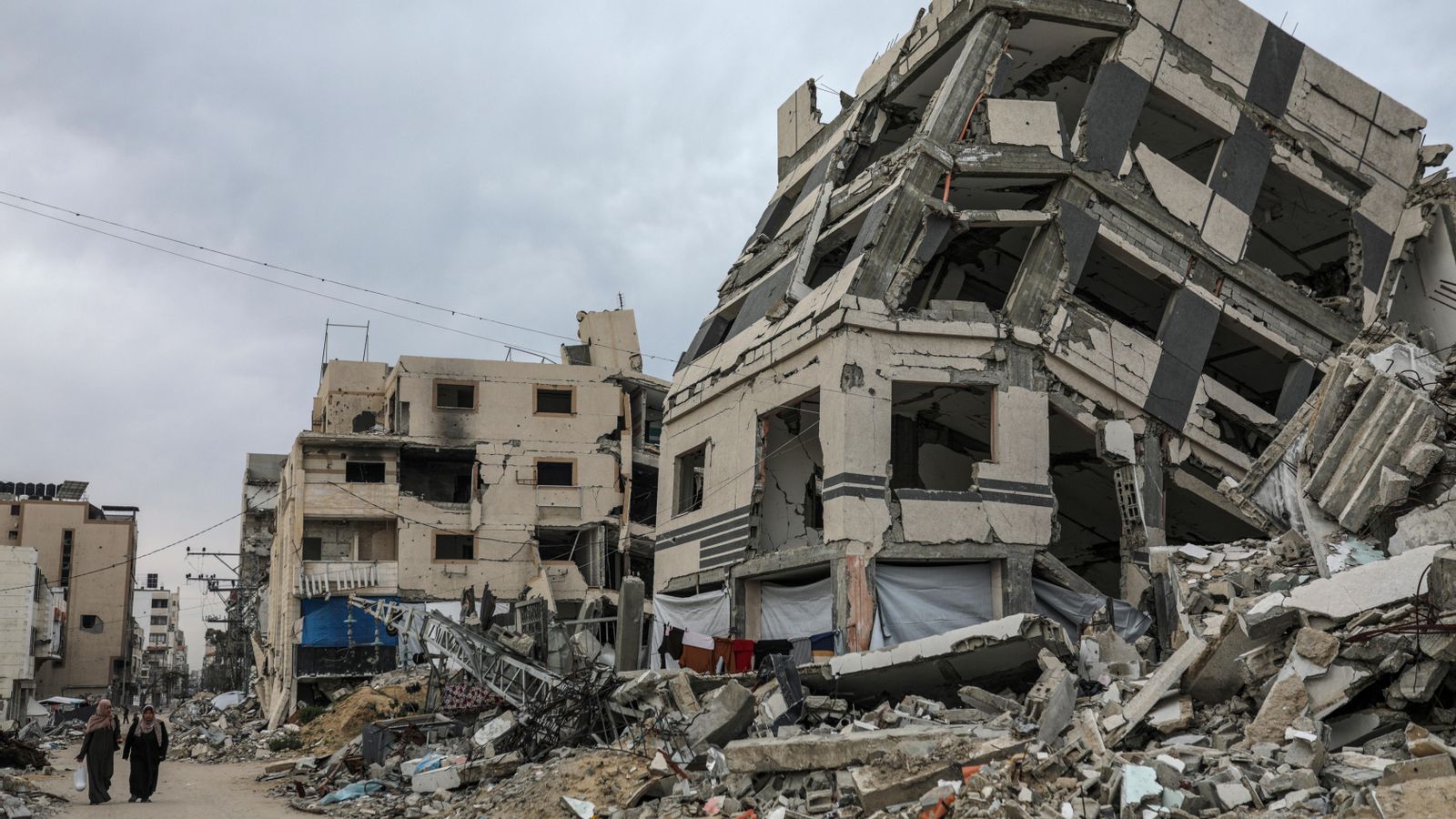 Palestines caminen per un carrer prop dels enderrocs d'edificis destruïts per l'exèrcit israelià a Gaza