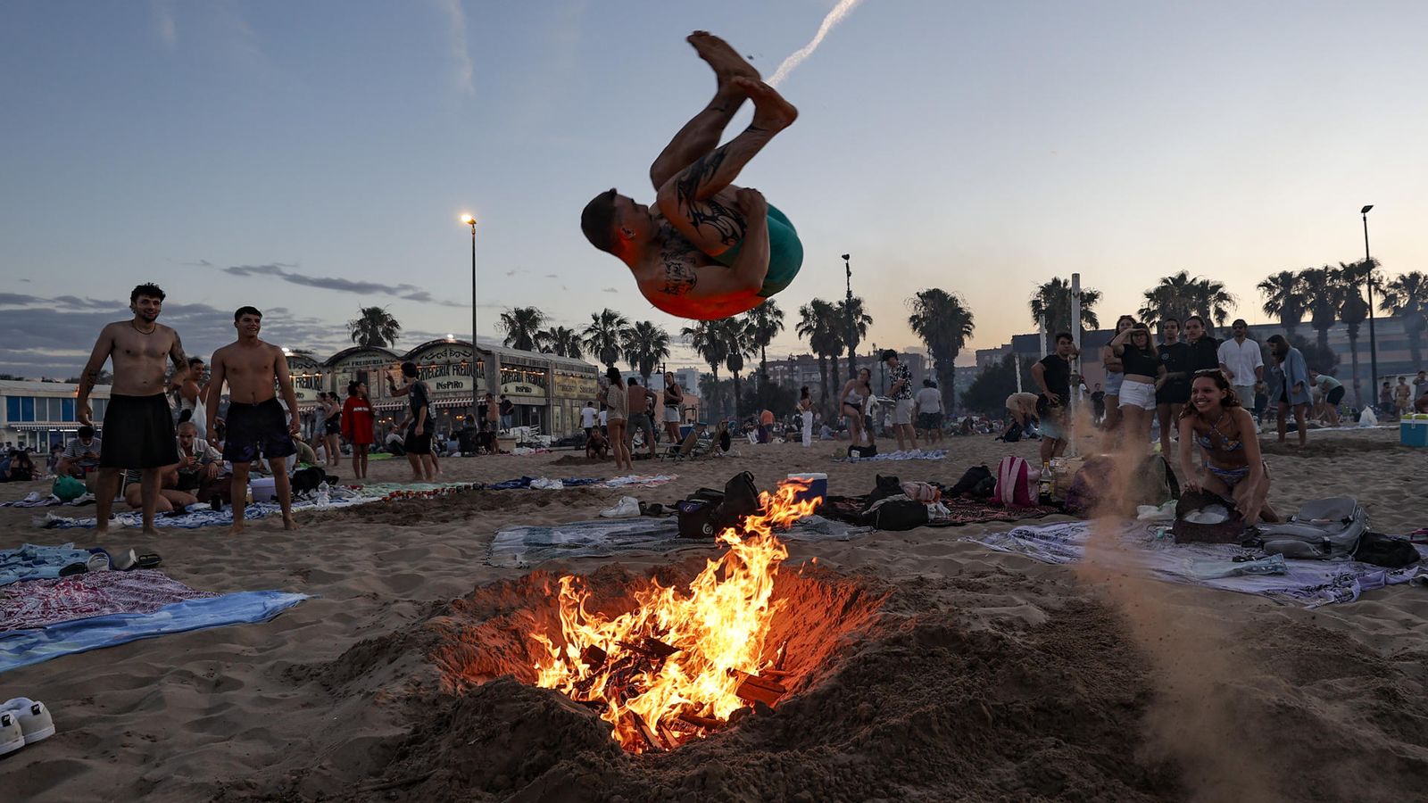Un jove salta una foguera a la platja de la Malva-rosa, a València