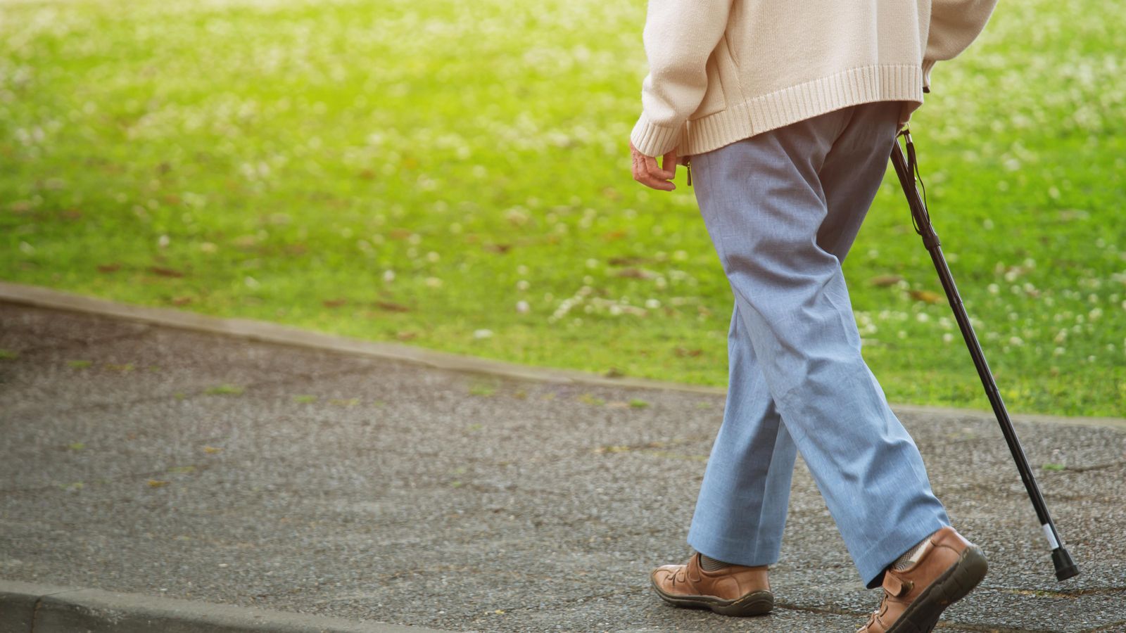 Un ancià camina amb un bastó