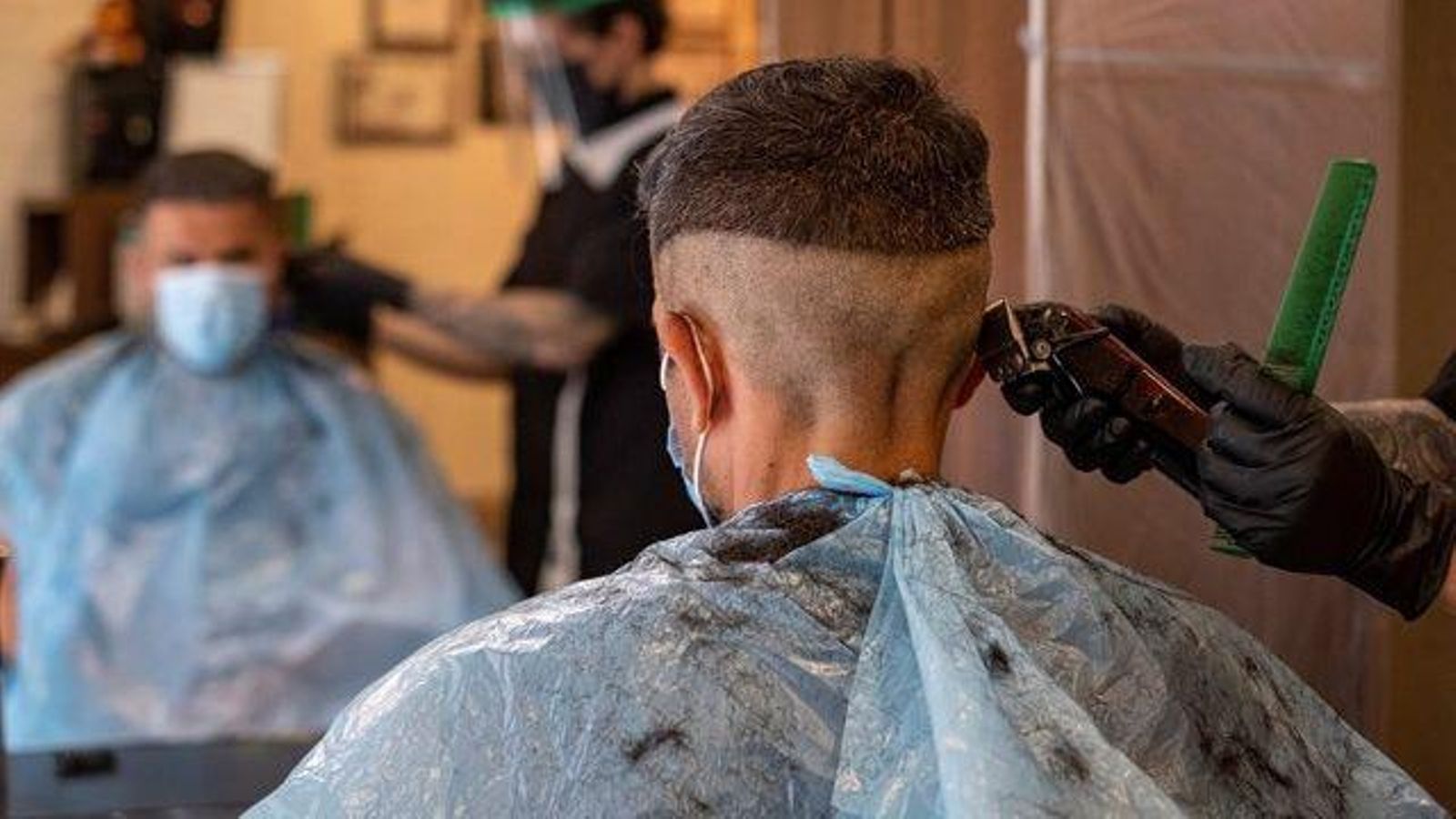 Un perruquer li tallar el cabell a un jove mitjançant la tècnica del degradat